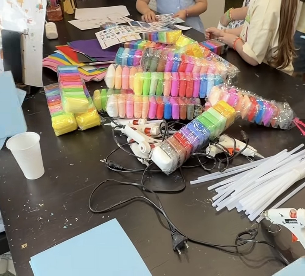 The workshop table before we start — foam clay in every colour, glue guns and sticker sheets laid out ready