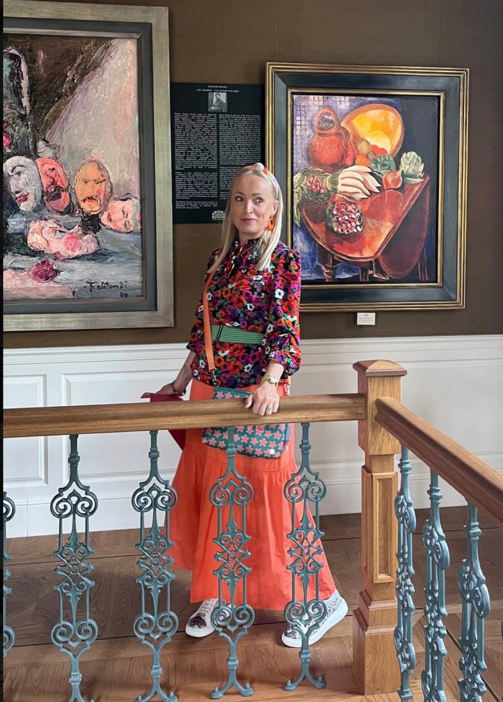 Elvira Koroleva in a gallery, between two paintings